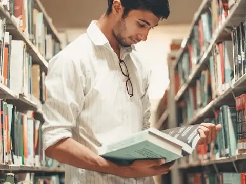 Kitaplıkların arasında kitap okuyan bir okur